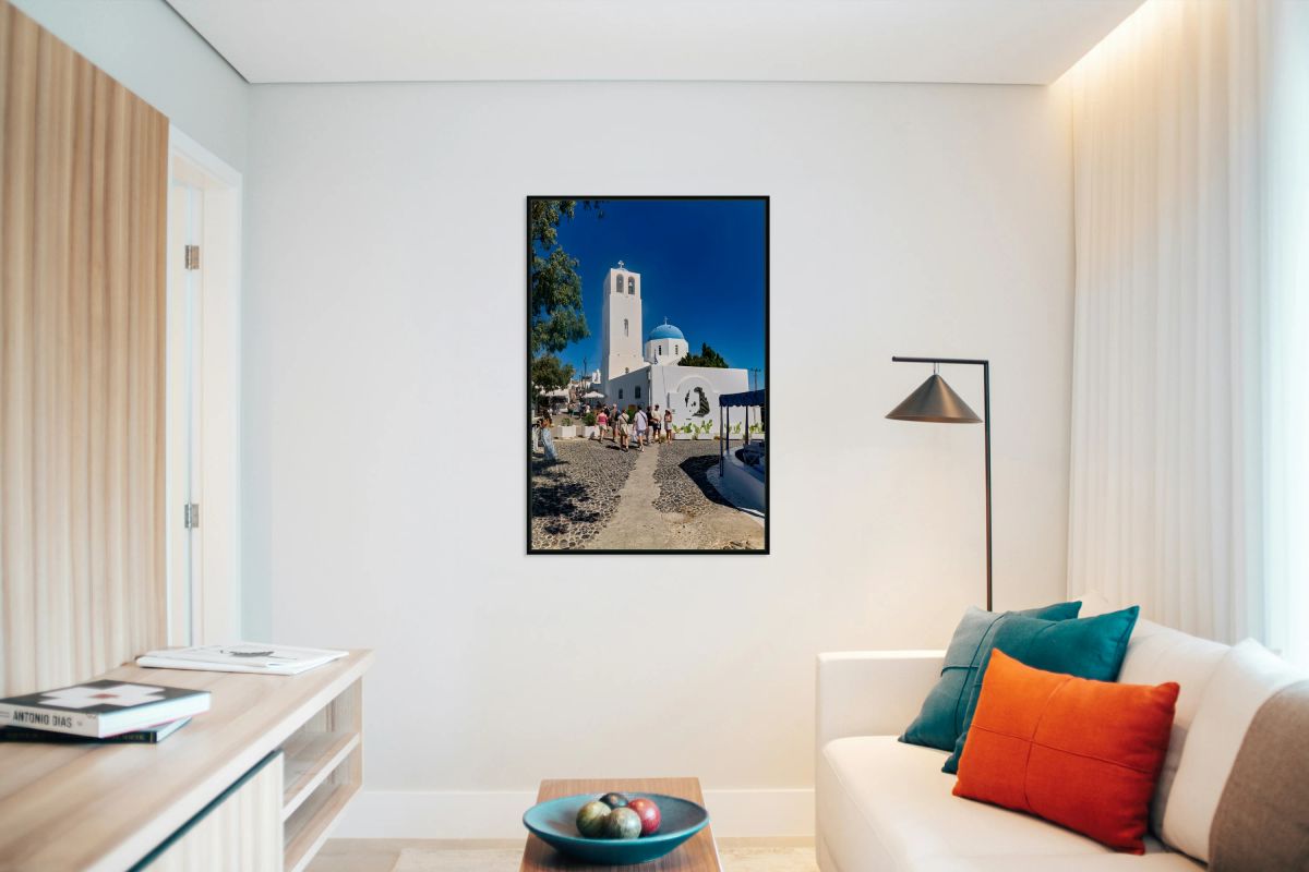 Greek village street with white church blue dome and tourists.
