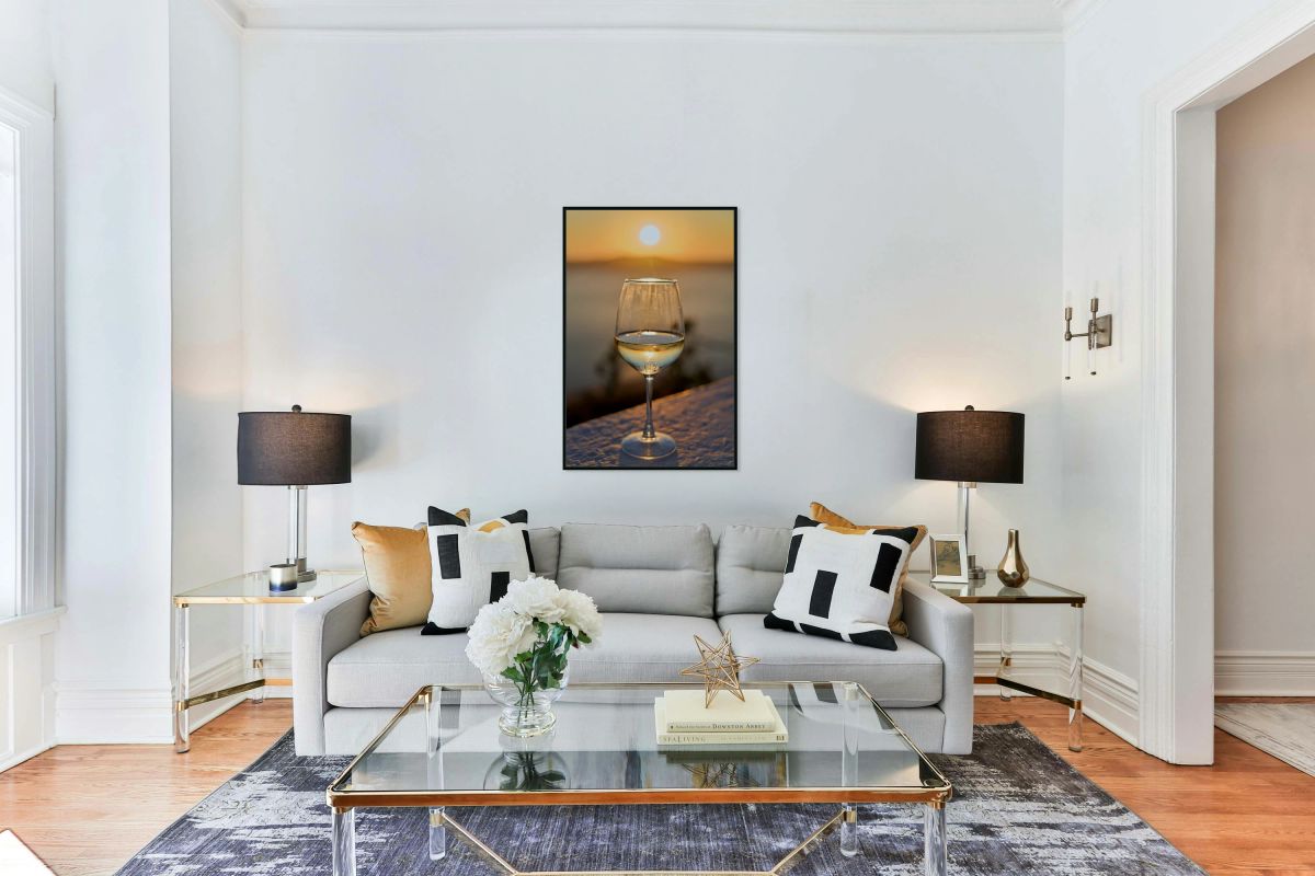 Wine glass reflecting golden sunset over water.