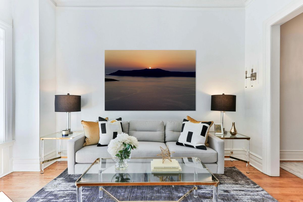 Golden sunset behind dark island calm ocean.