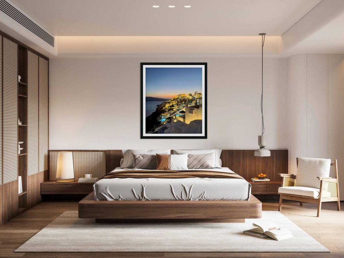 Illuminated cliffside village at sunset over the ocean.