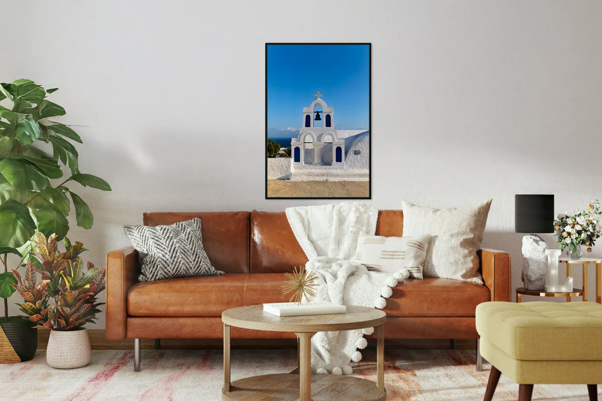White bell tower against blue sky and sea.