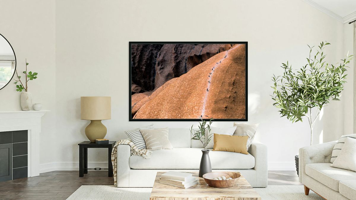 Hikers ascend Uluru using a chain ladder in Australia.