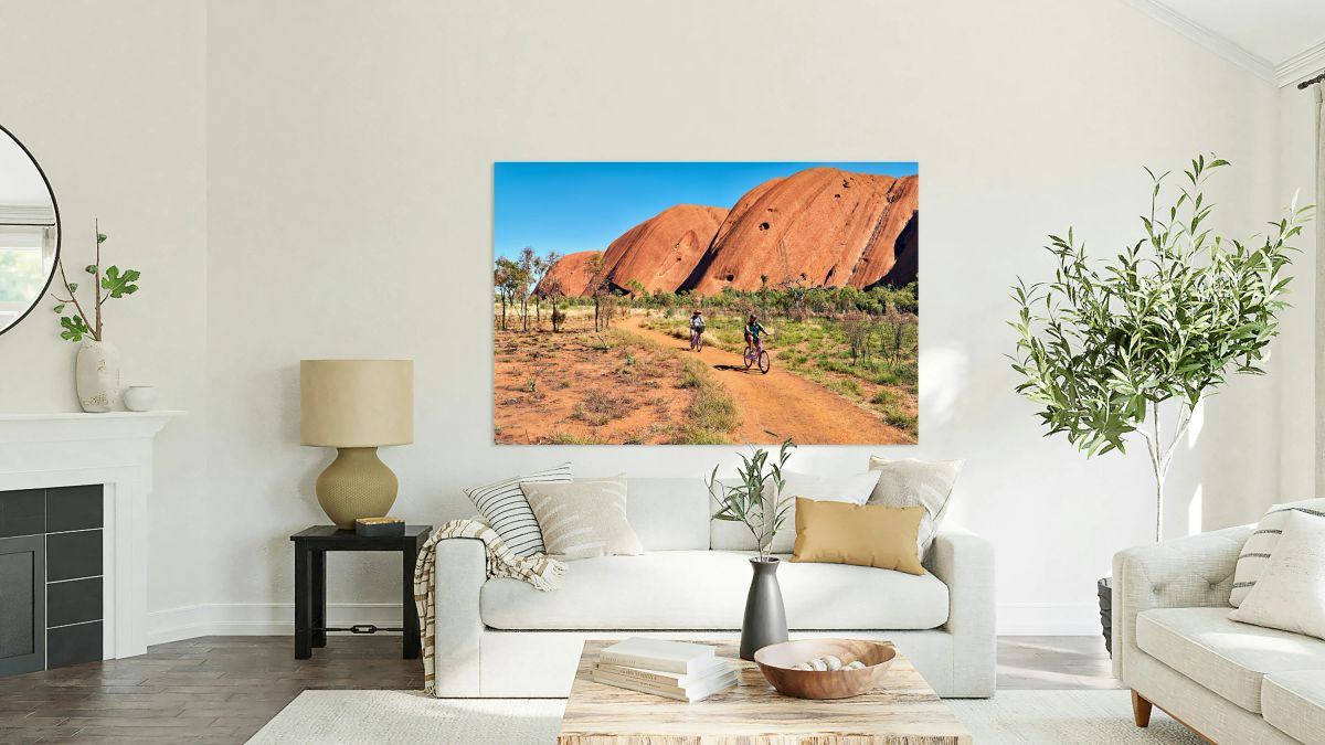 Two cyclists ride on a dirt path near Uluru Australia.