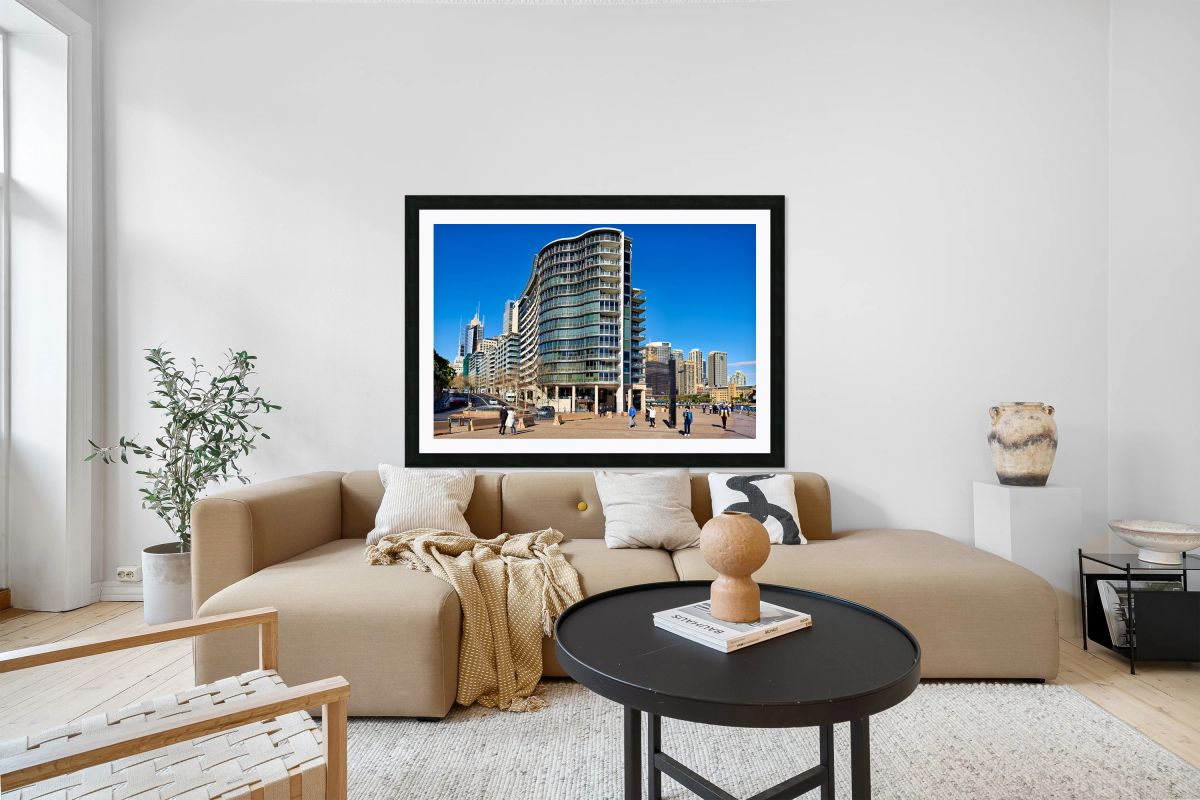 Modern curved building with balconies and city skyline.