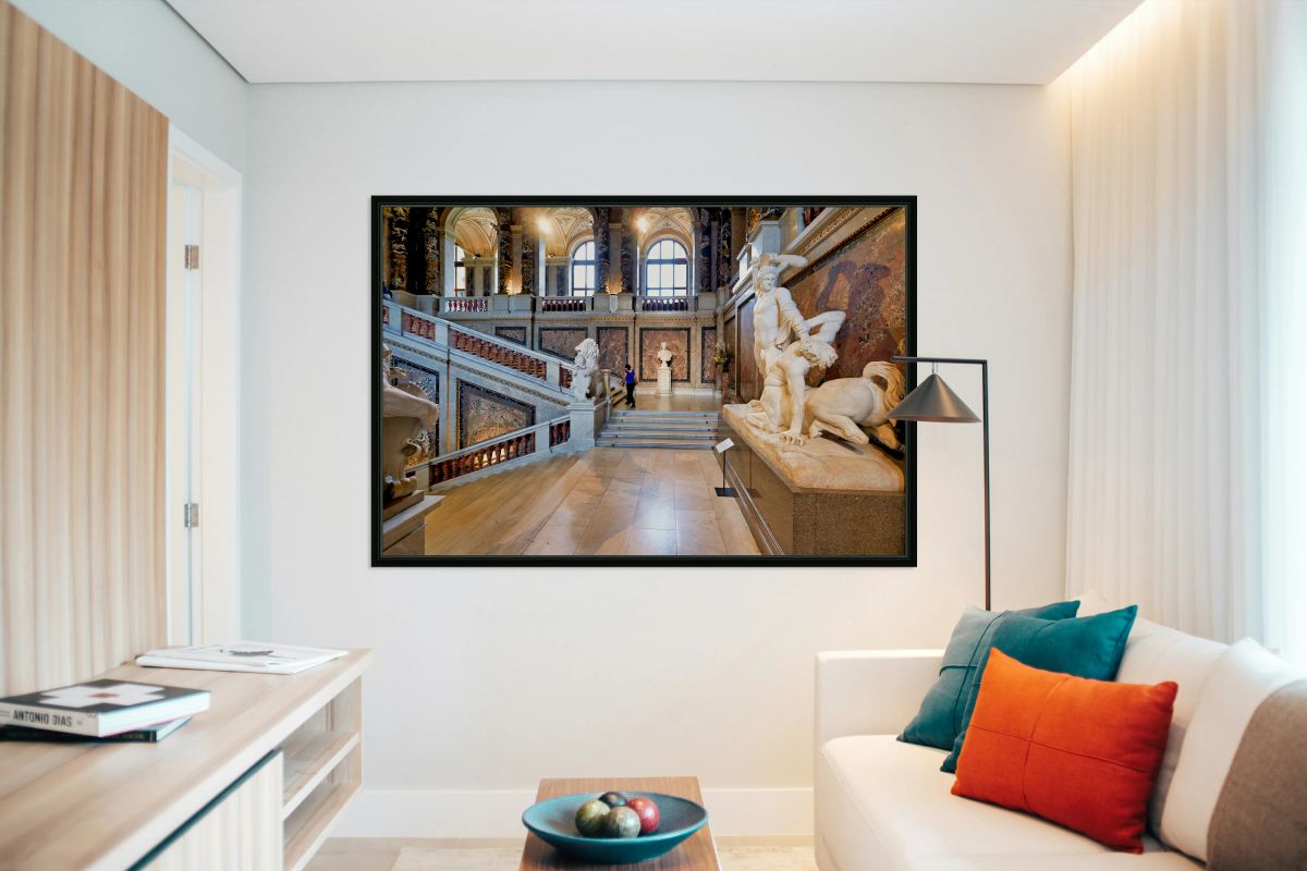 Ornate museum hall with statues grand staircase and visitor.