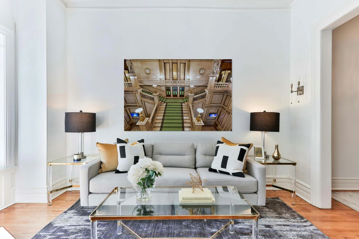 Ornate marble staircase with green carpet and classical statues.