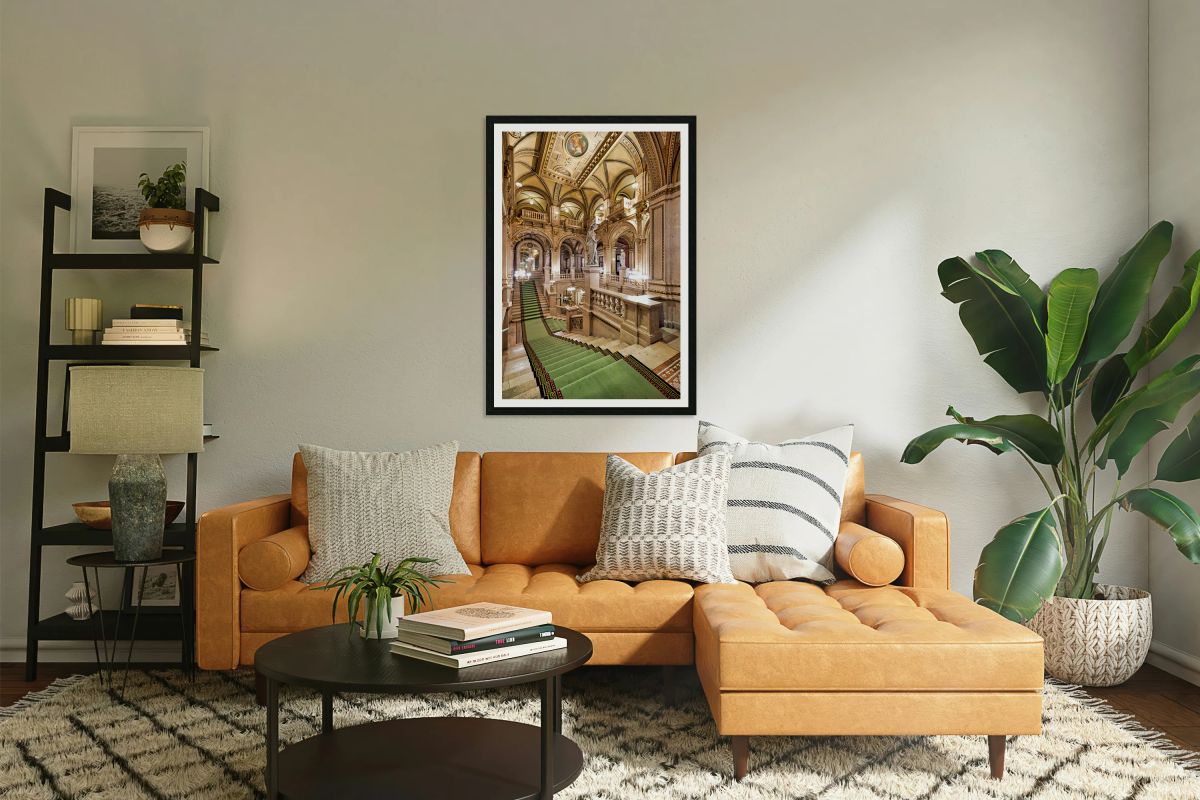 Ornate grand staircase with green carpet and classical statues.