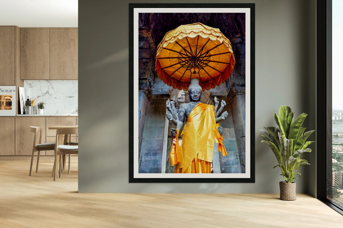 Ancient multi armed Vishnu statue with golden robe and umbrella.