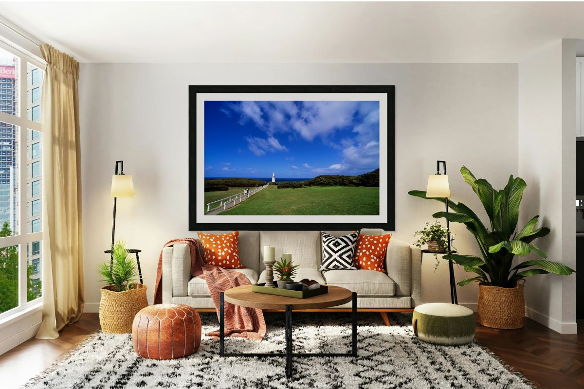 A path leads to a coastal lighthouse under blue skies.