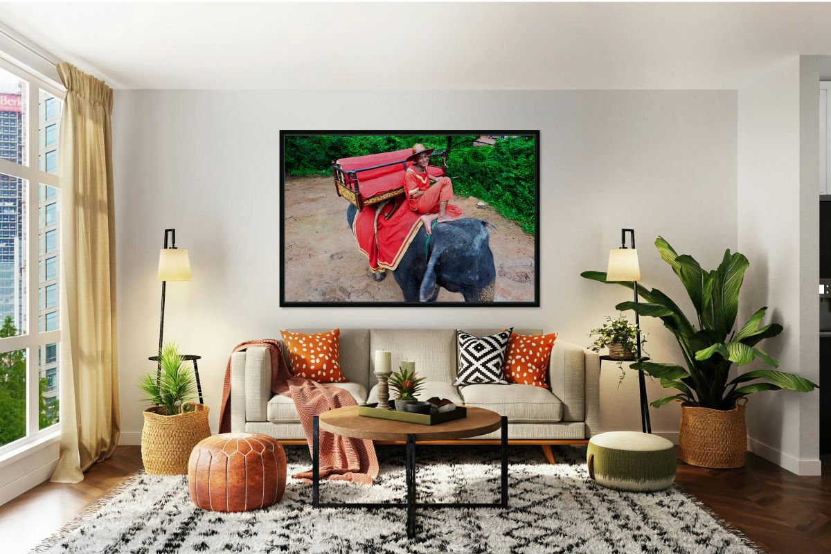Smiling mahout on elephant with ornate saddle in jungle.