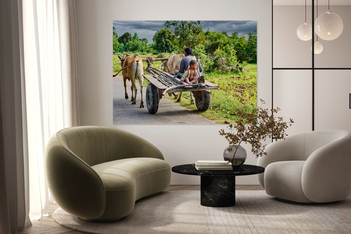 Man and child ride bullock cart on rural road.