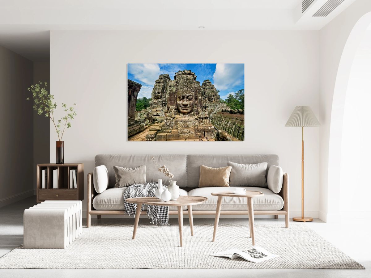 Ancient stone faces on Bayon Temple under a blue sky.
