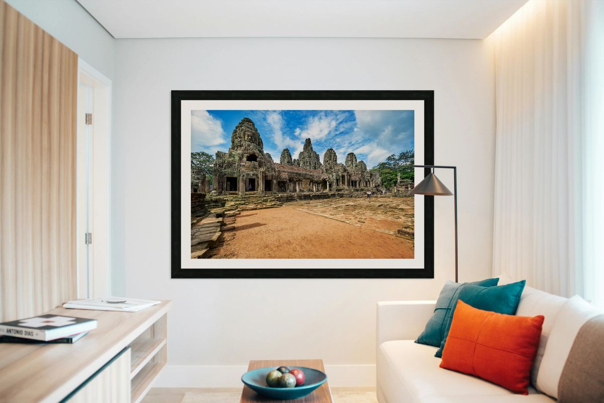 Ancient Bayon temple with stone faces under a blue sky.