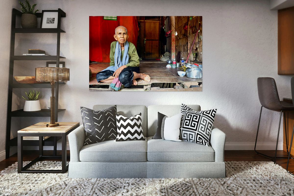 Elderly person sitting on floor in rustic dwelling.