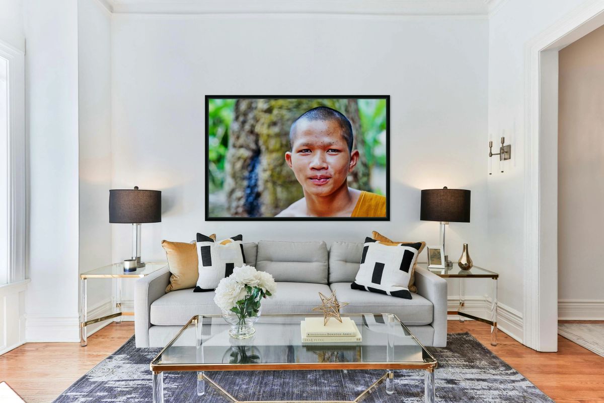 Young monk in orange robe looks at camera.