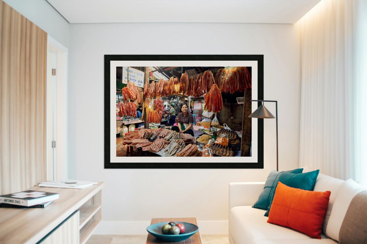 Woman sells dried fish at a bustling Cambodian market.