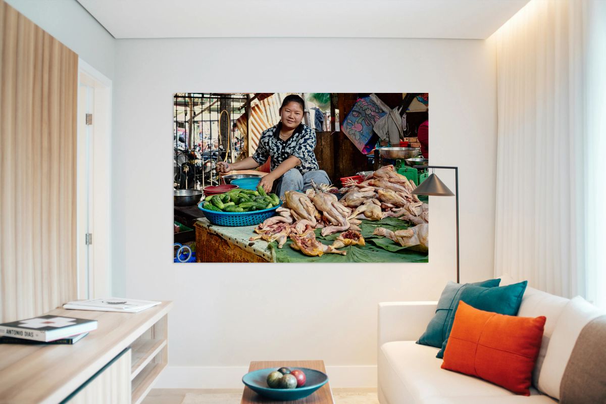 Woman sells raw chickens and cucumbers at a market.