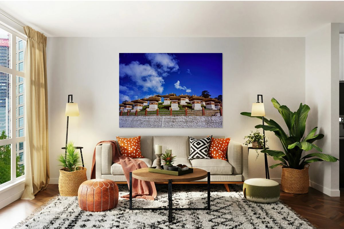 Traditional Bhutanese chortens on a green hill blue sky.