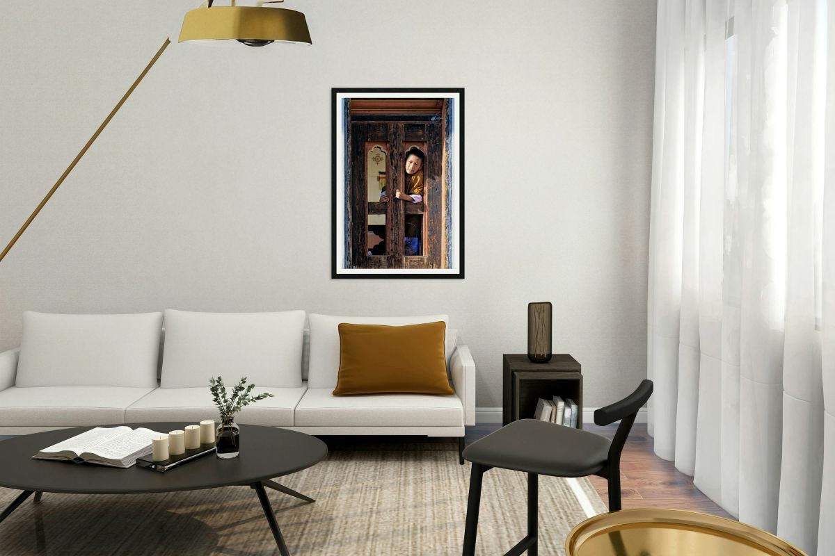 Bhutanese child peeking from ornate wooden window.