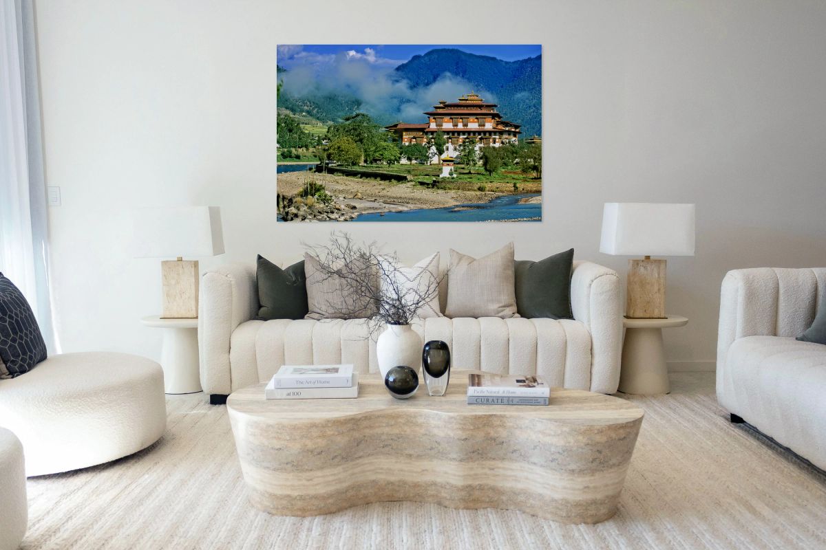 Bhutanese monastery by river with misty mountains.