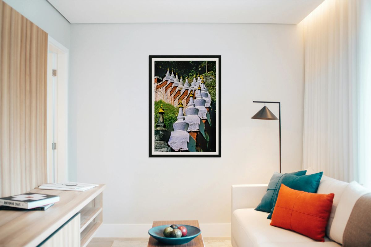 White stupas with golden spires on a green hillside.