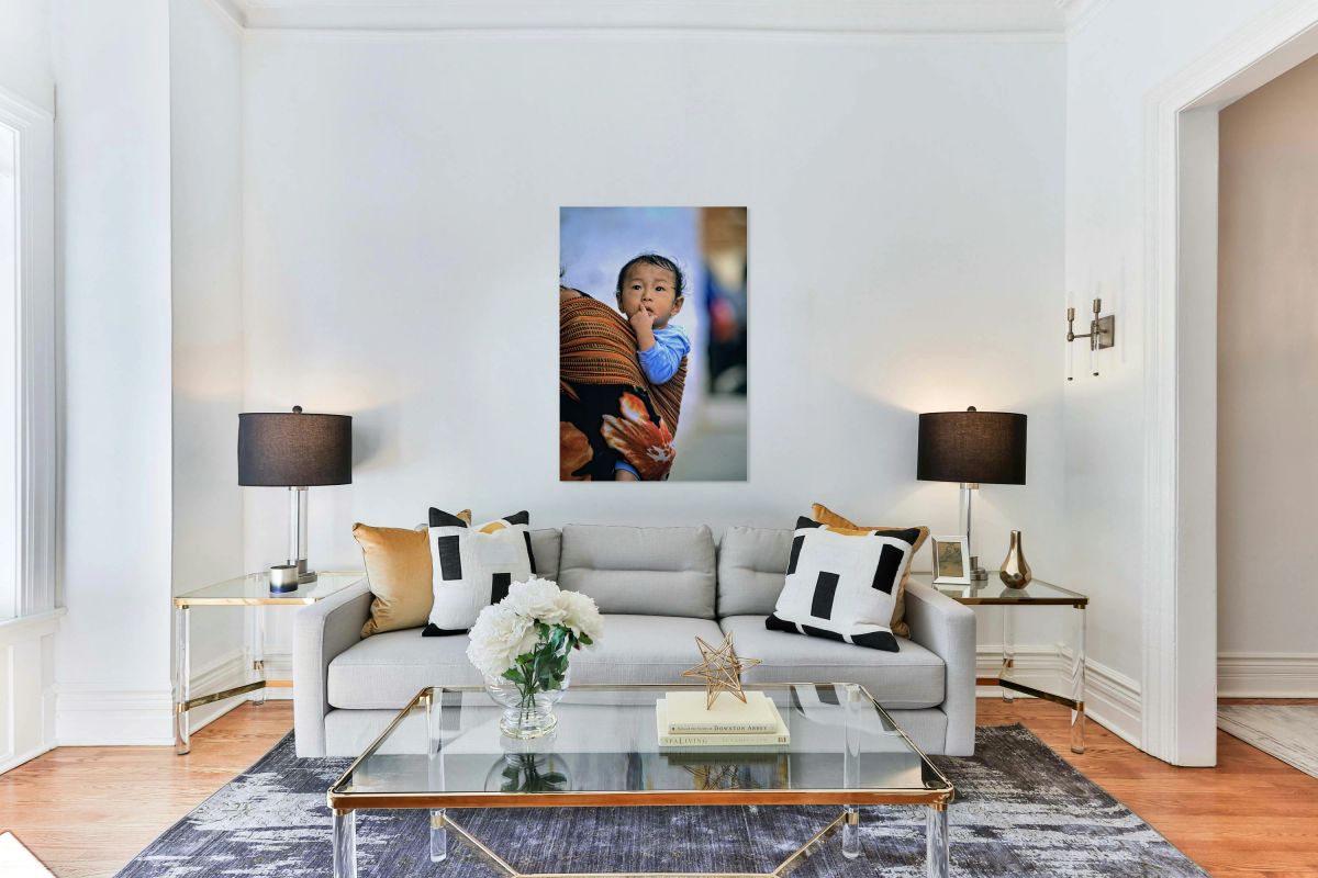 Curious child carried in a patterned fabric sling.