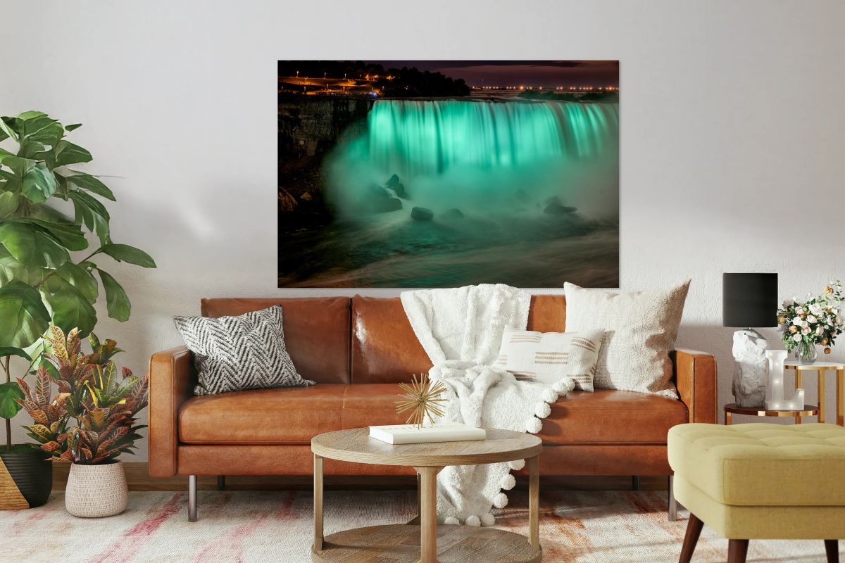 Niagara Falls illuminated green at night with spectators.