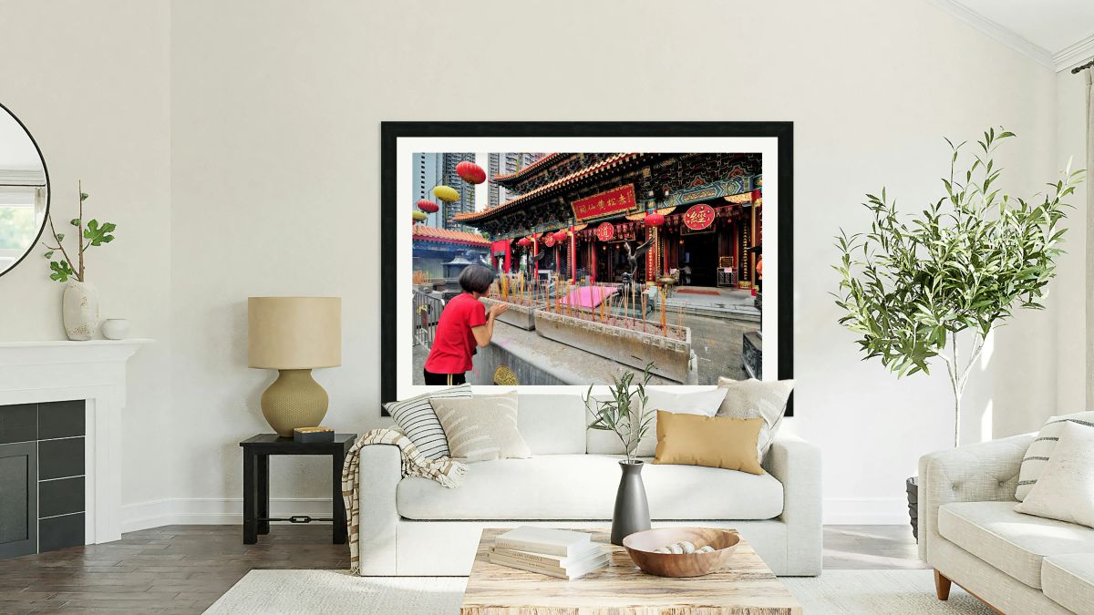 Woman prays with incense at colorful Chinese temple in Hong Kong