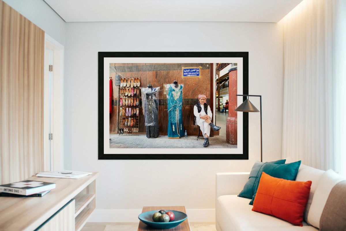 Man sits by shoes and dresses while relaxing in Dubai market