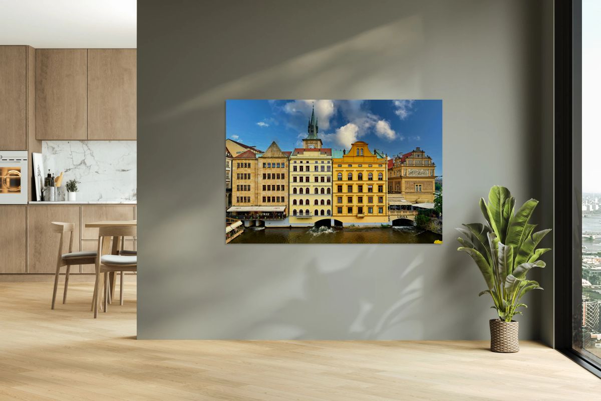 Historic Prague buildings and clock tower line a scenic river.