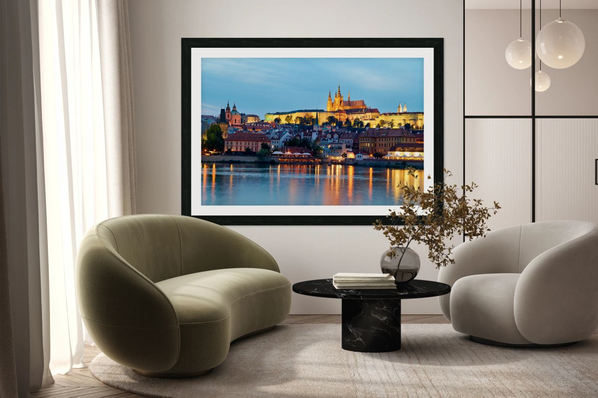 Prague cityscape at night with castle and river reflections.