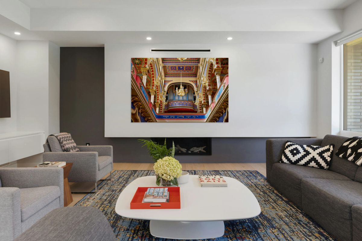 Ornate synagogue interior with organ and chandeliers.