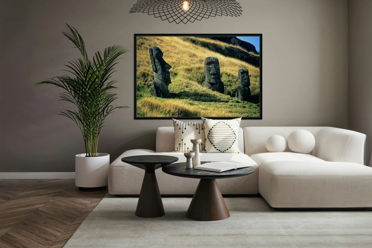 Three Moai statues on a grassy hillside.