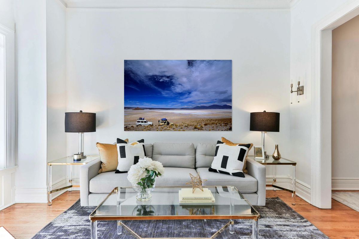 Vehicles traverse a vast arid salt flat landscape.