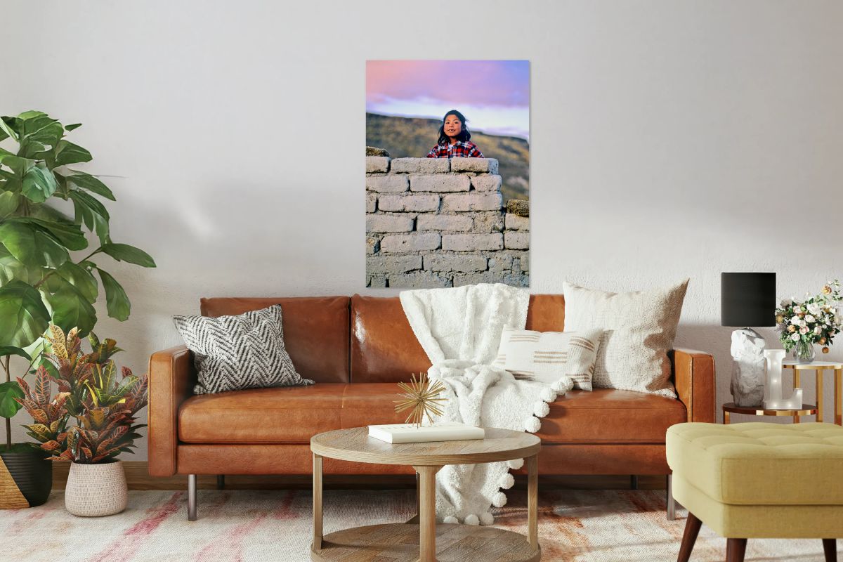 Young girl smiles over stone wall at sunset.