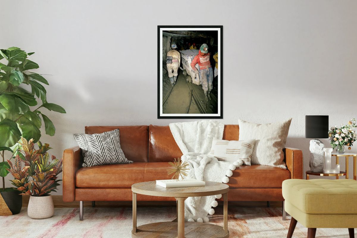 Miners pushing a loaded cart through a muddy underground mine.