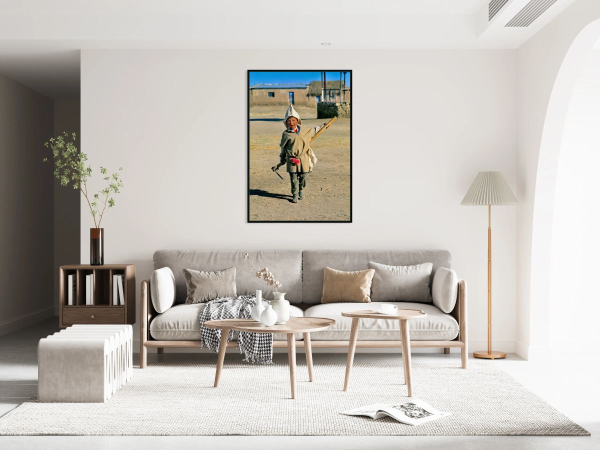 Indigenous boy with tools walks through a dusty village.