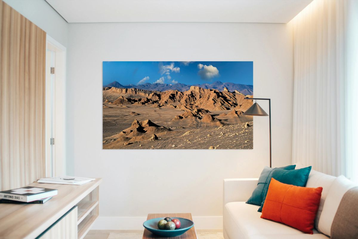 Rugged desert mountains under a clear blue sky with clouds.
