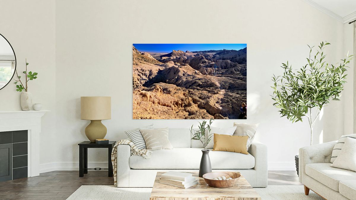 Hikers traverse a vast arid rocky desert landscape.