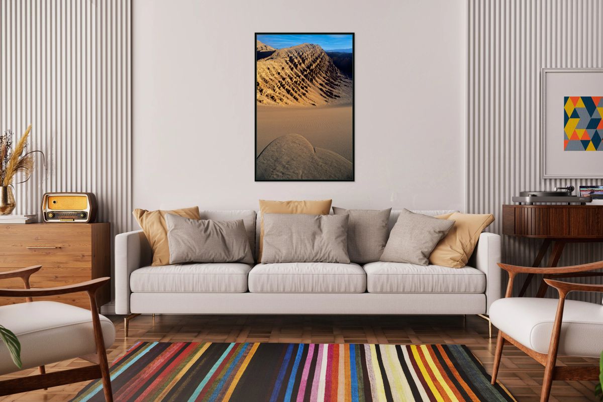 Eroded desert mountains and rippled sand under blue sky.
