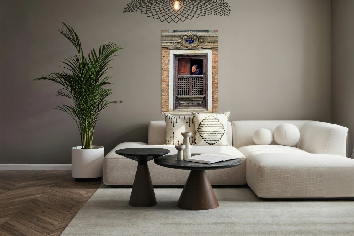 Woman in Kathmandu looks out from window in old building