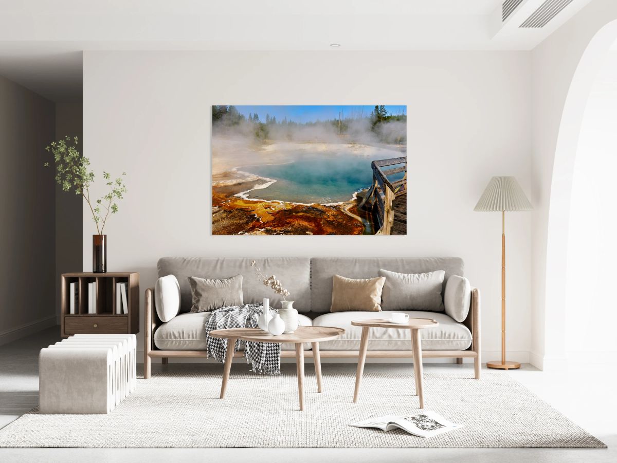 Steam rises from Abyss Pool as blue water reflects the surrounding landscape at Yellowstone National Park. Visitors explore the area nearby.