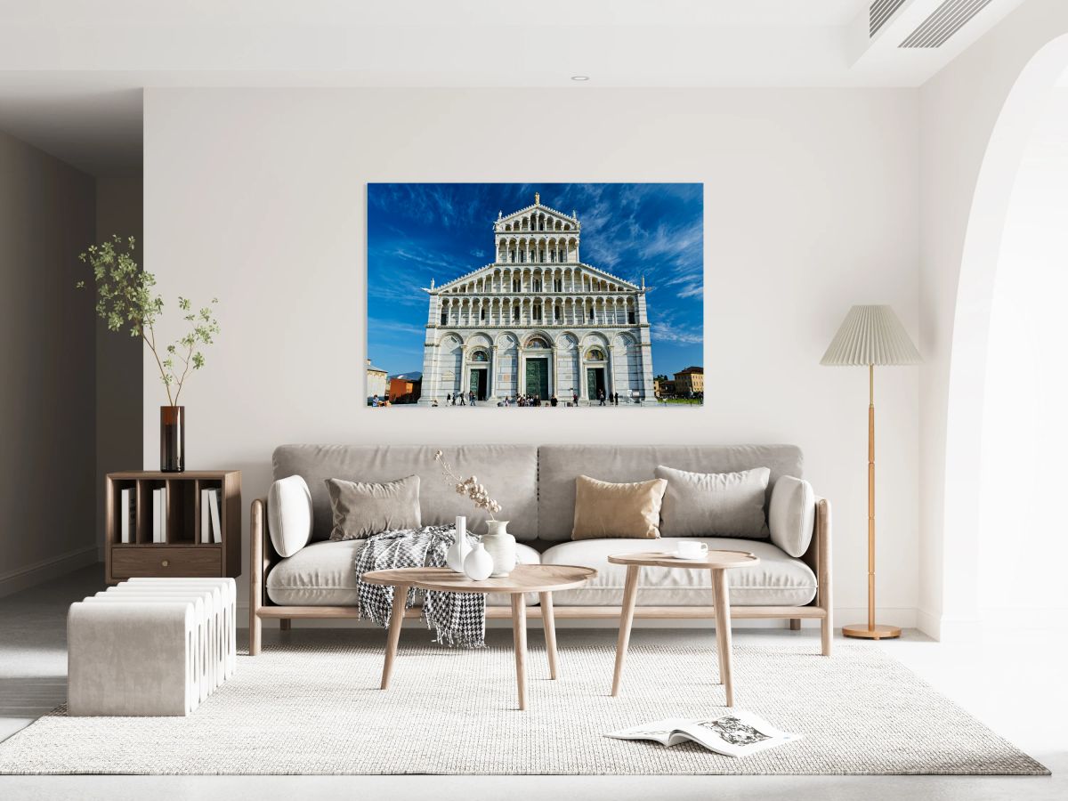Visitors walk around Pisa Cathedral in Piazza dei Miracoli. The tall structure stands under a blue sky. People enjoy the lively atmosphere.