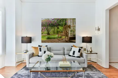 A vintage wooden rocking chair with a straw hat rests on a porch Reproduction