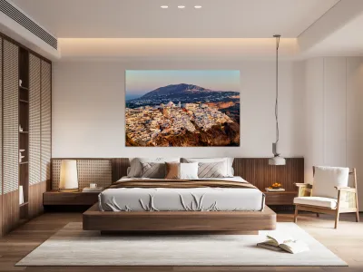 Santorini cliffside town at sunset with mountain backdrop. Reproduction