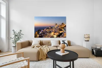 Santorinis Oia village glows at twilight by the sea. Reproduction