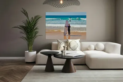 Surfer girl with surfboard on beach watching waves Reproduction