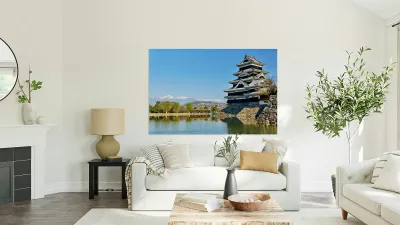 Matsumoto Castle stands beside water with mountains in the dista Reproduction