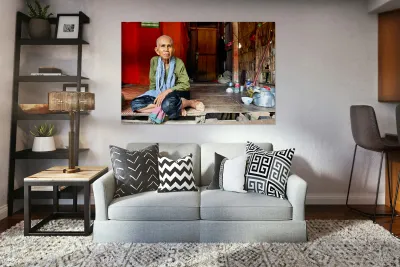 Elderly person sitting on floor in rustic dwelling. Reproduction