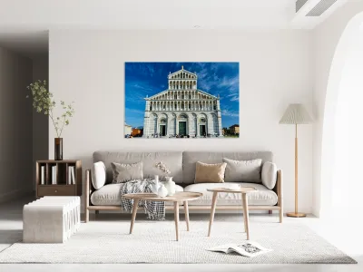 Visitors walk around Pisa Cathedral in Piazza dei Miracoli. The tall structure stands under a blue sky. People enjoy the lively atmosphere. Reproduction